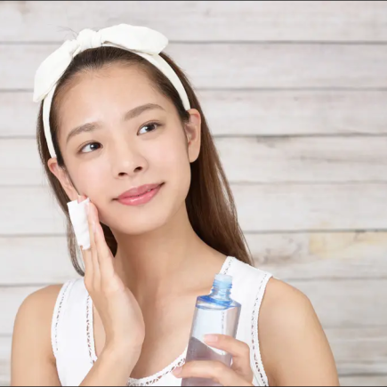 Wanita dengan kulit glowing alami, tersenyum dengan latar belakang alam.